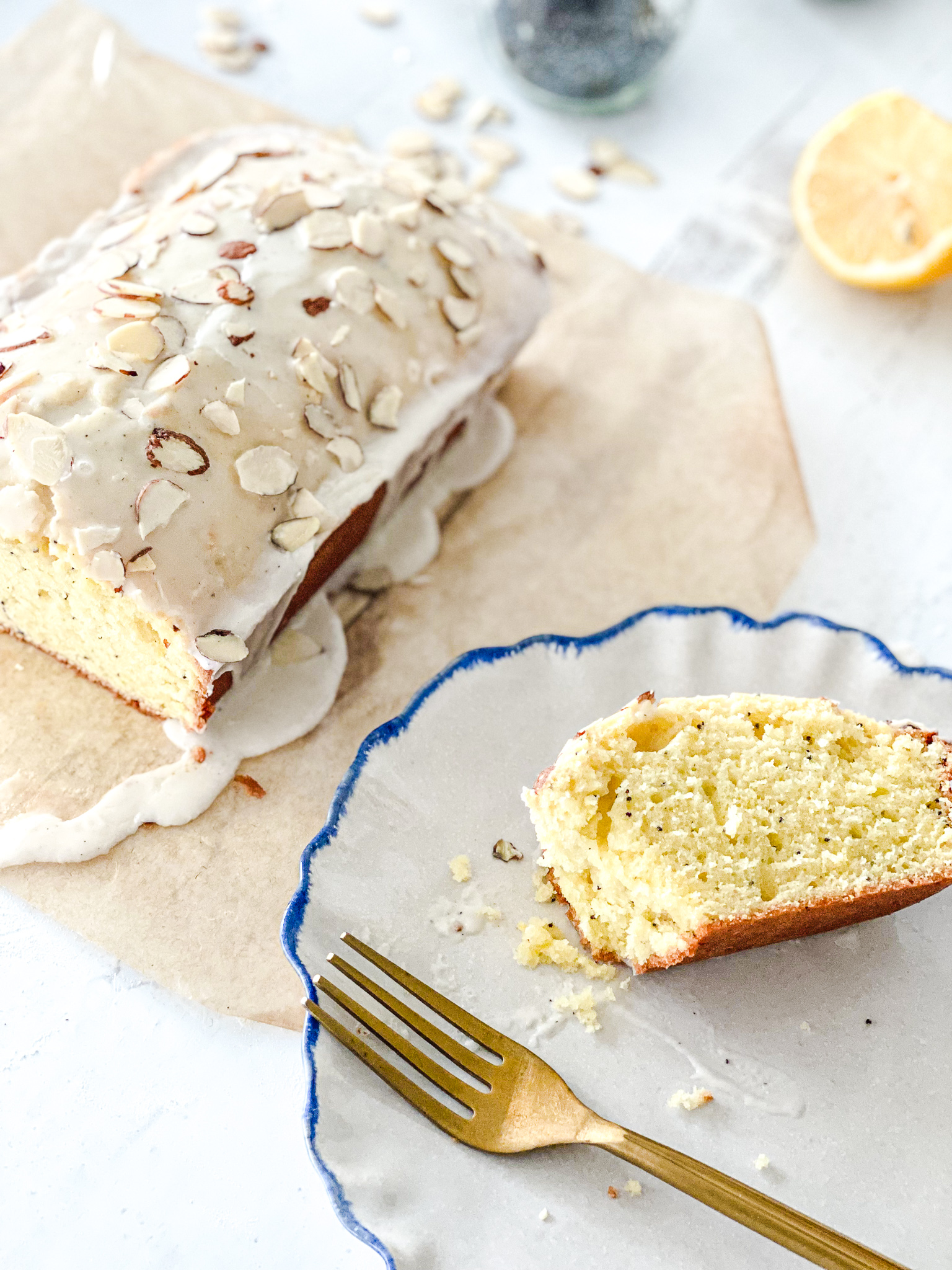 Poppyseed lemon loaf cake recipe with a vanilla bean glaze topped with sliced almonds.